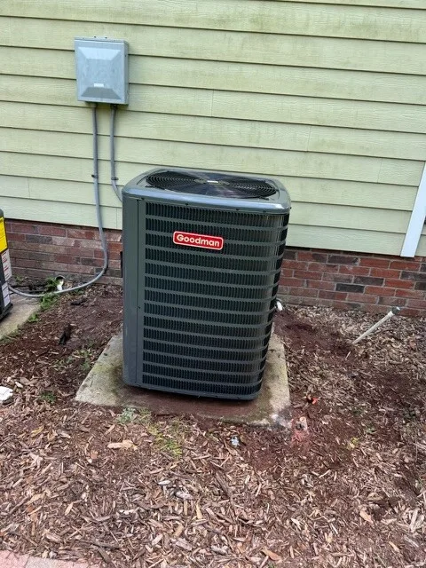 Newly installed AC condenser on a pad beside a home