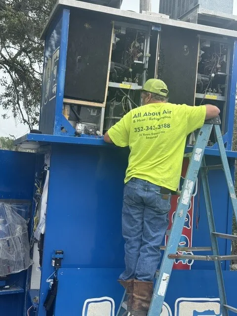 All About Air technician repairing the refrigeration system of an ice vending machine