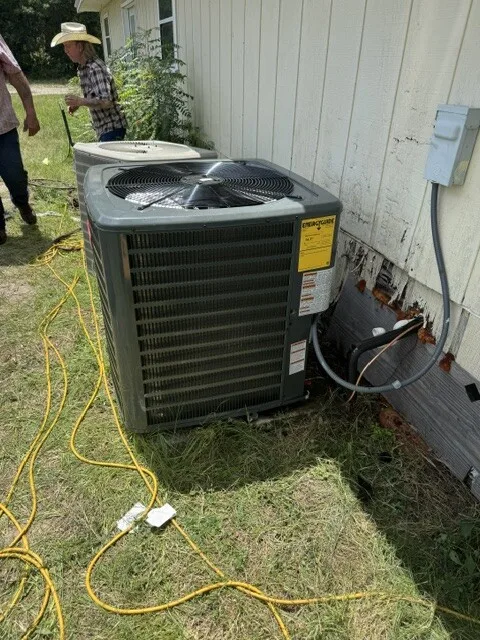 New AC condenser installed beside a mobile home, replacing the old unit