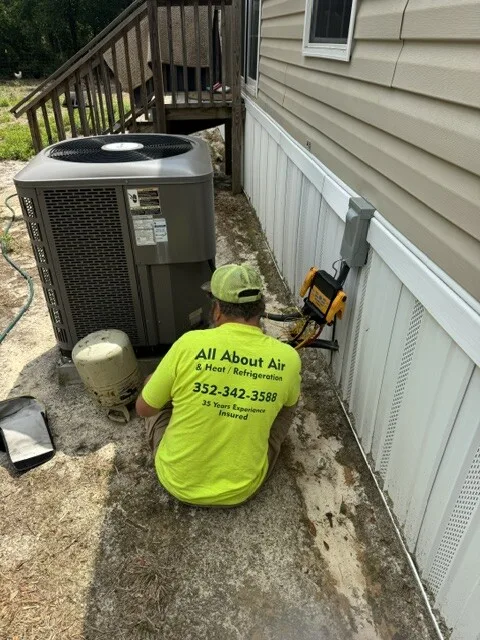 All About Air technician servicing an AC condenser at a mobile home