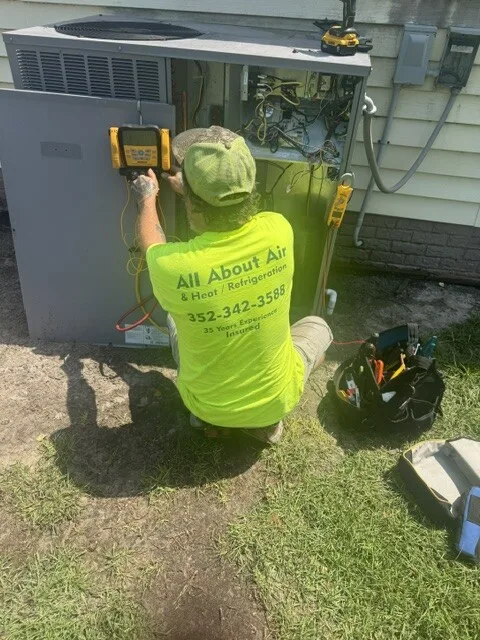 All About Air technician testing refrigerant pressure on an open packaged unit